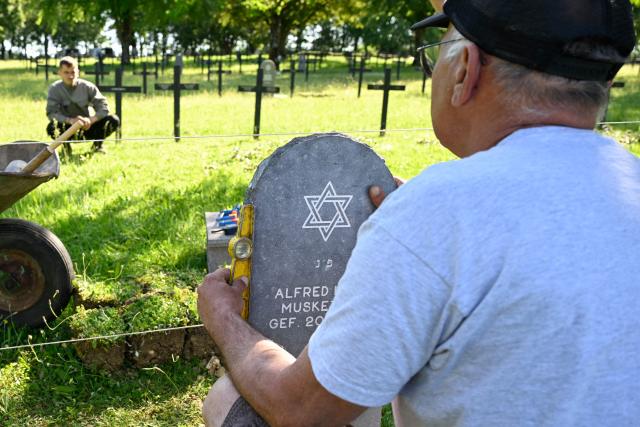 Members of "Service Entretien Sépultures Militaires Allemandes (SESMA)"  of Volksbund Deutsche Kriegsgräberfürsorge  (German War Graves Commission) replace gravestones of a Jewish soldiers from the First World War at the Consenvoye German WWI cemetery (Verdun battlefield) to better reflect their religion, in Consenvoye, northeastern France, on May 18, 2026. An unveiling ceremony will take place on June 3 , 2026. (Photo by Jean-Christophe Verhaegen / AFP)