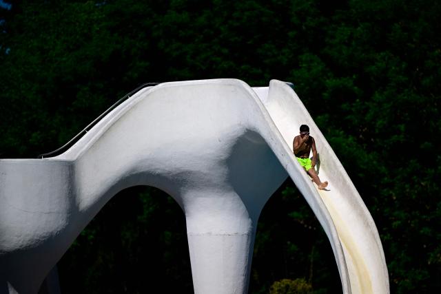 A boy uses a water slide in the Grugabad in Essen, western Germany, on May 28, 2026, as temperatures in Germany remain unsuaually high for the season.. (Photo by Ina FASSBENDER / AFP)