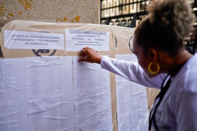 An employee of the national registry searches a polling station on a chart in Bogota on May 28, 2026. Colombia will hold presidential elections on May 31, 2026. (Photo by Sergio ANGEL / AFP)