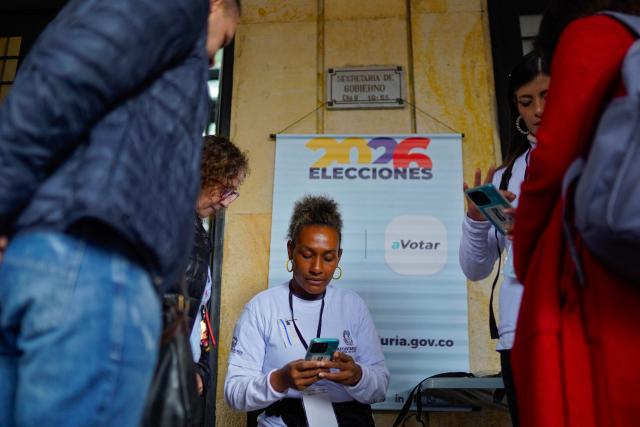 An employee of the national registry helps people search their polling station in Bogota on May 28, 2026. Colombia will hold presidential elections on May 31, 2026. (Photo by Sergio ANGEL / AFP)