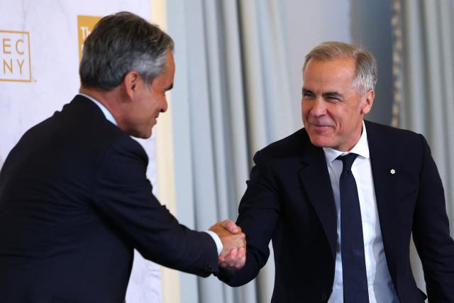 Canadian Prime Minister Mark Carney (R) greets Danish author Nader Mousavizadeh at the Economic Club in New York on May 28, 2026. (Photo by ANGELA WEISS / AFP)