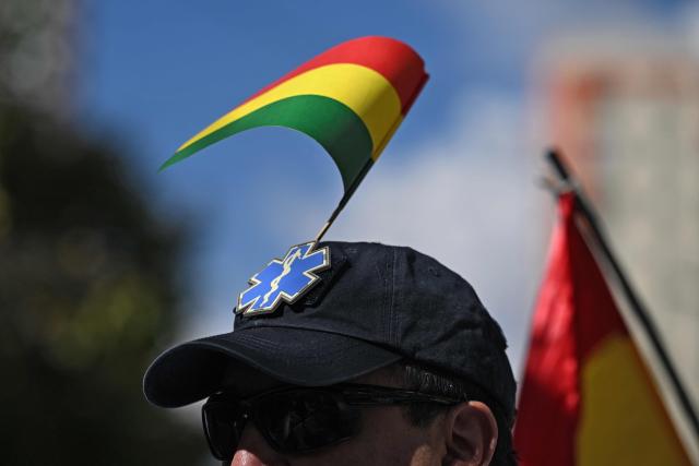 A healthcare worker with a Bolivian national flag takes part in a protest against roadblocks and access blockades to the city carried out by demonstrators opposing Bolivian President Rodrigo Paz, denouncing that shortages of food, medicines and oxygen are affecting patient care, in La Paz, Bolivia, on May 28, 2026. (Photo by Marvin RECINOS / AFP)