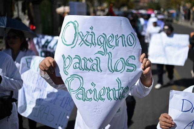 A healthcare worker holds a sign reading "Oxygen for patients" during a protest against roadblocks and access blockades to the city carried out by demonstrators opposing Bolivian President Rodrigo Paz, denouncing that shortages of food, medicines and oxygen are affecting patient care, in La Paz, Bolivia, on May 28, 2026. (Photo by Marvin RECINOS / AFP)