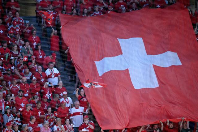 Switzerland's supporters hold a huge national flag in the stands prior to the IIHF Ice Hockey Men's World Championship quarter-final match between Switzerland and Sweden at the Swiss Life Arena in Zurich, on May 28, 2026. (Photo by SEBASTIEN BOZON / AFP)