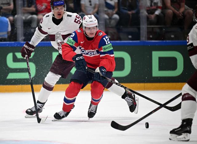 Latvia's defender #55 Roberts Mamcics (L) and Norway's forward #12 Noah Steen vie for the puck during the IIHF Ice Hockey Men's World Championship quarter-final match between Norway and Latvia in Fribourg, Switzerland on May 28, 2026. (Photo by Fabrice COFFRINI / AFP)