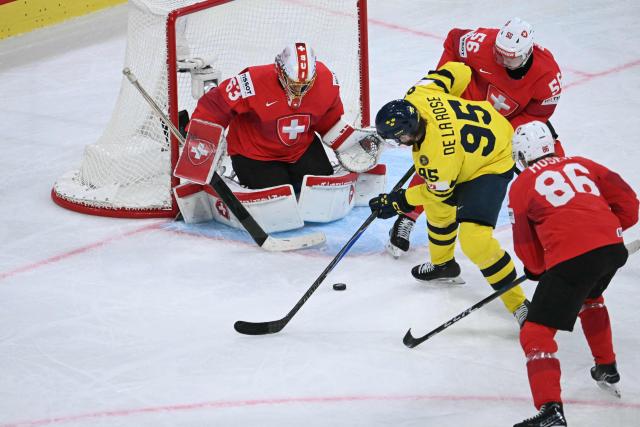 Sweden's forward #95 Jacob de la Rose fights for the puck with Switzerland's goalkeeper #63 Leonardo Genoni (L), Switzerland's defender #56 Tim Berni (2nd R) and Switzerland's defender #86 Janis Moser during the IIHF Ice Hockey Men's World Championship quarter-final match between Switzerland and Sweden at the Swiss Life Arena in Zurich, on May 28, 2026. (Photo by SEBASTIEN BOZON / AFP)