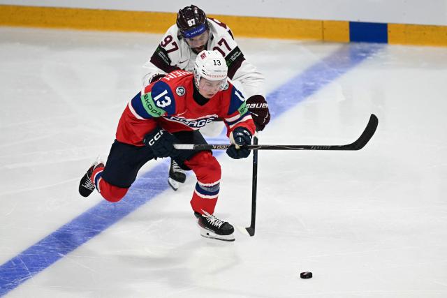 Norway's forward #13 Petter Vesterheim (L) and Latvia's forward #97 Haralds Egle vie for the puck during the IIHF Ice Hockey Men's World Championship quarter-final match between Norway and Latvia in Fribourg, Switzerland on May 28, 2026. (Photo by Fabrice COFFRINI / AFP)