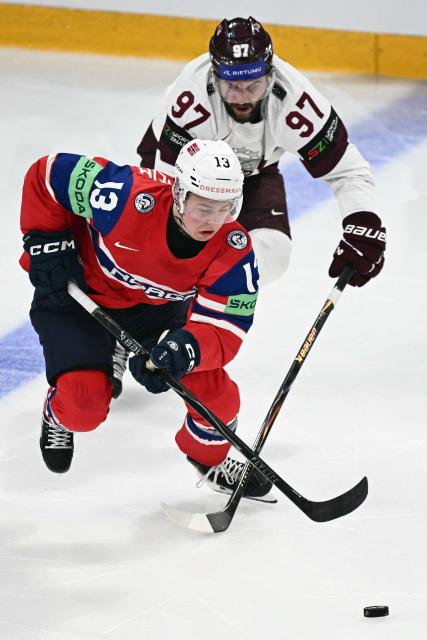 Norway's forward #13 Petter Vesterheim (L) and Latvia's forward #97 Haralds Egle vie for the puck during the IIHF Ice Hockey Men's World Championship quarter-final match between Norway and Latvia in Fribourg, Switzerland on May 28, 2026. (Photo by Fabrice COFFRINI / AFP)
