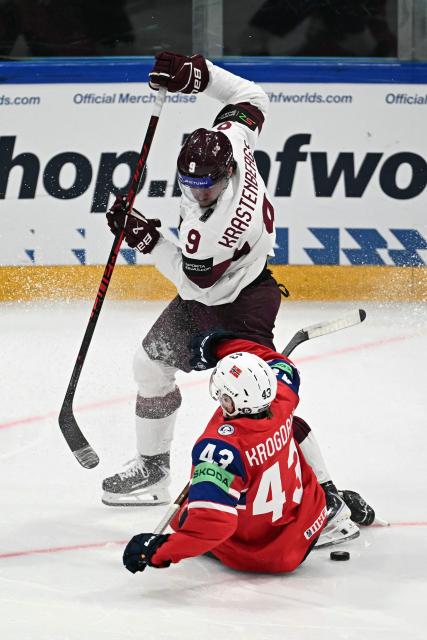 Latvia's forward #09 Renars Krastenbergs (R) and Norway's defender #43 Max Krogdahl crash as they vie for the puck during the IIHF Ice Hockey Men's World Championship quarter-final match between Norway and Latvia in Fribourg, Switzerland on May 28, 2026. (Photo by Fabrice COFFRINI / AFP)