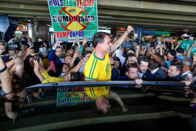 Brazilian Senator Flavio Bolsonaro greets supporters upon his arrival from the US at the International Airport in Brasilia, on May 28, 2026. (Photo by Sergio Lima / AFP)