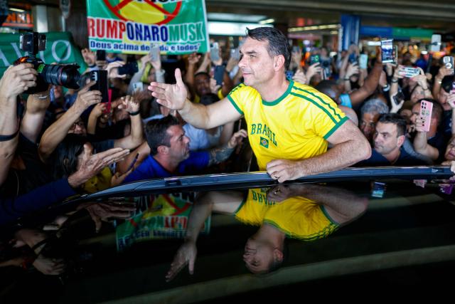 Brazilian Senator Flavio Bolsonaro greets supporters upon his arrival from the US at the International Airport in Brasilia, on May 28, 2026. (Photo by Sergio Lima / AFP)