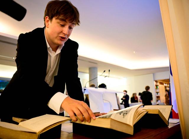 Matis Bloch, the great-grandson of French historian Marc Bloch, reacts as he looks at books at a ceremony at the French embassy in Berlin, during which three German cultural institutions hand over seven books to the descendants of Marc Bloch (1886–1944) and his wife Simonne Vidal (1894–1944), on May 28, 2026. Marc Bloch, a member of the Resistance, was executed by the Gestapo on June 16, 1944. The restitution of the books was organized by the Berlin State Library – Prussian Cultural Heritage, with the support of the French Commission for the Restitution of Cultural Property and Compensation for the Victims of Anti-Semitic Expropriations (CIVS). (Photo by Tobias SCHWARZ / AFP)