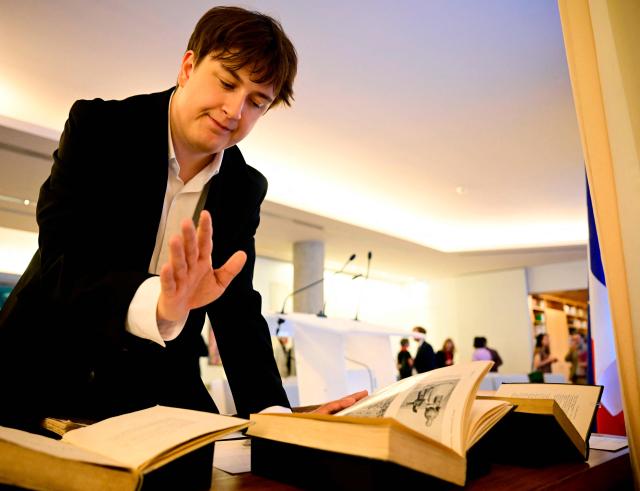 Matis Bloch, the great-grandson of French historian Marc Bloch, reacts as he looks at books at a ceremony at the French embassy in Berlin, during which three German cultural institutions hand over seven books to the descendants of Marc Bloch (1886–1944) and his wife Simonne Vidal (1894–1944), on May 28, 2026. Marc Bloch, a member of the Resistance, was executed by the Gestapo on June 16, 1944. The restitution of the books was organized by the Berlin State Library – Prussian Cultural Heritage, with the support of the French Commission for the Restitution of Cultural Property and Compensation for the Victims of Anti-Semitic Expropriations (CIVS). (Photo by Tobias SCHWARZ / AFP)