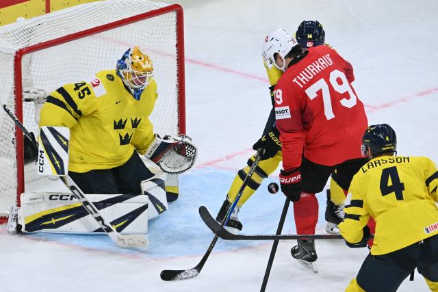 Sweden's goalkeeper #45 Magnus Hellberg (L) and Switzerland's forward #79 Calvin Thurkauf (2nd R) eye the puck during the IIHF Ice Hockey Men's World Championship quarter-final match between Switzerland and Sweden at the Swiss Life Arena in Zurich, on May 28, 2026. (Photo by SEBASTIEN BOZON / AFP)