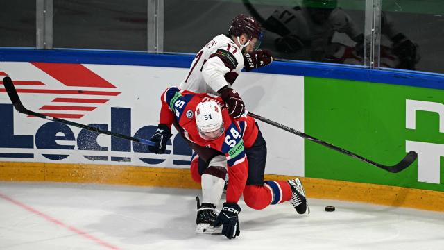 Norway's defender #54 Sander Hurrod (front) and Latvia's forward #17 Martins Dzierkals vie for the puck during the IIHF Ice Hockey Men's World Championship quarter-final match between Norway and Latvia in Fribourg, Switzerland on May 28, 2026. (Photo by Fabrice COFFRINI / AFP)