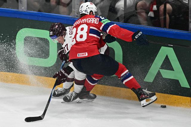 Latvia's forward #37 Oskars Lapinskis (L) and Norway's forward #28 Michael Brandsegg-Nygard vie for the puck during the IIHF Ice Hockey Men's World Championship quarter-final match between Norway and Latvia in Fribourg, Switzerland on May 28, 2026. (Photo by Fabrice COFFRINI / AFP)
