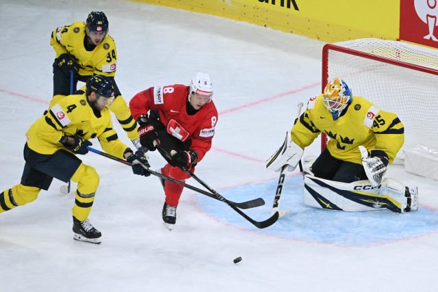 Switzerland's forward #8 Simon Knak (C) fights for the puck with Sweden's defender #4 Jacob Larsson (L) and Sweden's goalkeeper #45 Magnus Hellberg during the IIHF Ice Hockey Men's World Championship quarter-final match between Switzerland and Sweden at the Swiss Life Arena in Zurich, on May 28, 2026. (Photo by SEBASTIEN BOZON / AFP)