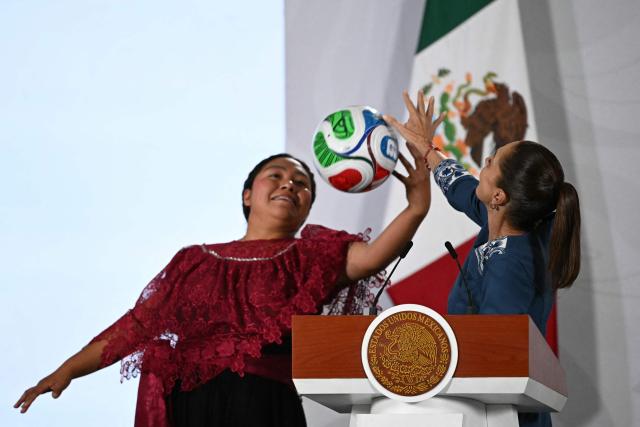 Mexico's President Claudia Sheinbaum (R) tries to stop a ball during a ball skills demonstration by contest winner Yolette Cervantes at the awards ceremony of the "Represent Mexico at the World Cup Opening" contest, launched in March, at the National Palace in Mexico City on May 29, 2026. (Photo by YURI CORTEZ / AFP)