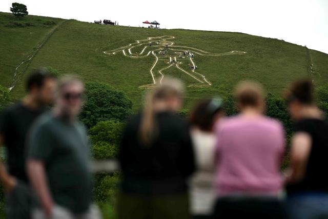 People look on as volunteers work on the once-a-decade restoration of the Cerne Abbas Giant, in Dorchester, southern England on May 29, 2026. (Photo by Ben STANSALL / AFP)