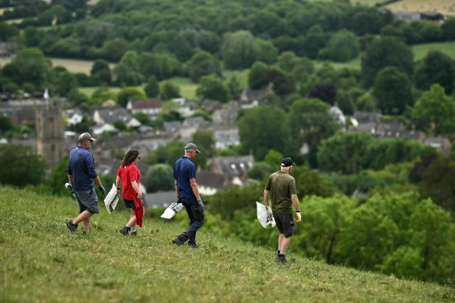 Volunteers carry plastic bags down the hill before collecting old chalk during the once-a-decade restoration of the Cerne Abbas Giant, in Dorchester, southern England on May 29, 2026. (Photo by Ben STANSALL / AFP)