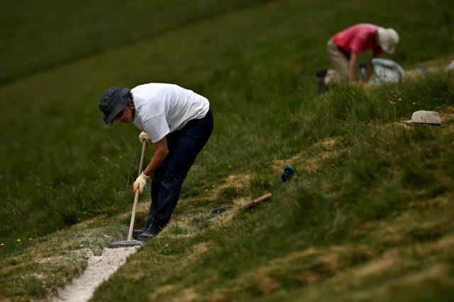 A volunteer works on the once-a-decade restoration of the Cerne Abbas Giant, in Dorchester, southern England on May 29, 2026. (Photo by Ben STANSALL / AFP)