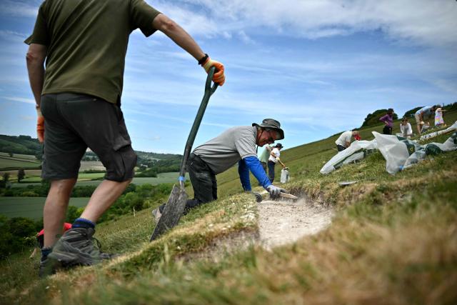 Volunteers work on the once-a-decade restoration of the Cerne Abbas Giant, in Dorchester, southern England on May 29, 2026. (Photo by Ben STANSALL / AFP)