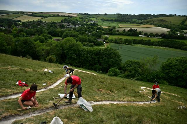 Volunteers work on the once-a-decade restoration of the Cerne Abbas Giant, in Dorchester, southern England on May 29, 2026. (Photo by Ben STANSALL / AFP)