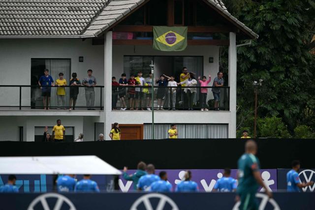 Fans of Brazil's national football team watch the players train from a neighbouring house overlooking the training ground during a training session at the Granja Comary training center in Teresopolis, Rio de Janeiro, Brazil, on May 29, 2026, ahead of the FIFA World Cup 2026. (Photo by Mauro PIMENTEL / AFP)