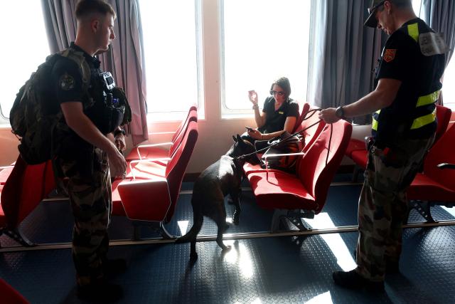 A French gendarme patrols with a sniffer dog of French Gendarmerie's K9 Unit on a ferry connecting Le Verdon-sur-Mer (Gironde) to Royan (Charente-Maritime) during an anti-drug trafficking operation, off the coast of Royan, south-western France on May 29, 2026. (Photo by ROMAIN PERROCHEAU / AFP)