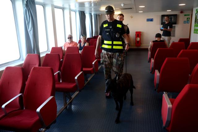 A French gendarme patrols with a sniffer dog of French Gendarmerie's K9 Unit on a ferry connecting Le Verdon-sur-Mer (Gironde) to Royan (Charente-Maritime) during an anti-drug trafficking operation, off the coast of Royan, south-western France on May 29, 2026. (Photo by ROMAIN PERROCHEAU / AFP)