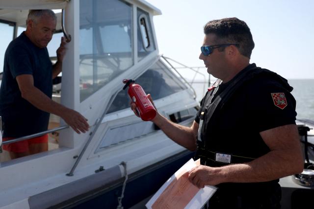 A French Maritime Gendarme inspects a fire extinguisher on a private boat off the coast of Royan, south-western France on May 29, 2026. (Photo by ROMAIN PERROCHEAU / AFP)