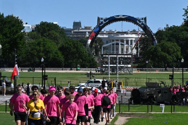 Visitors walk near the White House on The Elipse as cranes work on the construction of a structure on the South Lawn of the White House in Washington, DC, on May 29, 2026, for the upcoming UFC fight that US President Donald Trump will host as part of the 250th anniversary of the United States. It has played host to countless world leaders and moments in history. Now US President Donald Trump has built a huge cage-fighting arena on the White House's South Lawn. (Photo by Anne LEBRETON / AFP)