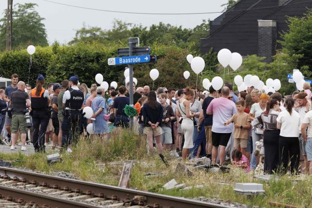 Attendees hold white balloons as they pay their respects during a wake ceremony to commemorate the victims of the May 26, 2026 accident between a train and a school bus at the railway crossing Vierhuizen, in Buggenhout on May 29, 2026. A train on May 26, 2026 hit a school minibus killing four people, including two children in a "horrific accident" in northern Belgium, authorities said. The children aged 15 and 12, were killed by the impact alongside the 49-year-old driver and a 27-year-old supervisor, according to Lisa De Wilde, a spokeswoman for the prosecutor's office. (Photo by NICOLAS MAETERLINCK / Belga / AFP) / Belgium OUT
