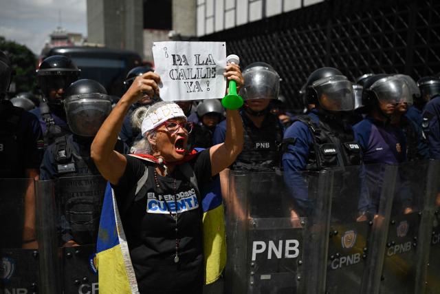 A woman holds a sign reading "Take to the streets now" during a protest demanding better living conditions and higher pensions in Caracas on May 29, 2026. (Photo by Federico PARRA / AFP)