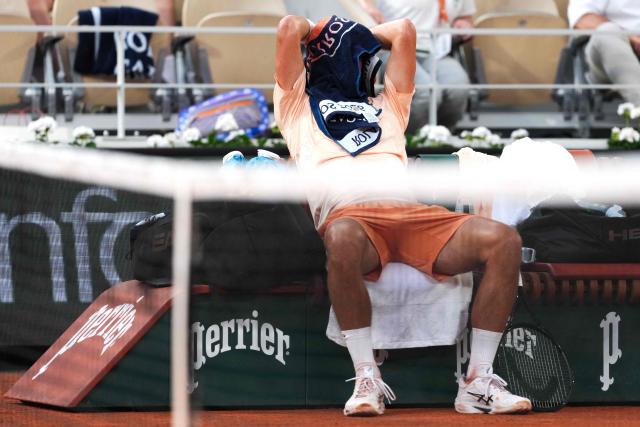 Serbia's Novak Djokovic hides under a towel while sitting in between games Brazil's Joao Fonseca during their men's singles match on day 6 of the French Open tennis tournament on Court Philippe-Chatrier at the Roland-Garros Complex in Paris on May 29, 2026. (Photo by Dimitar DILKOFF / AFP)