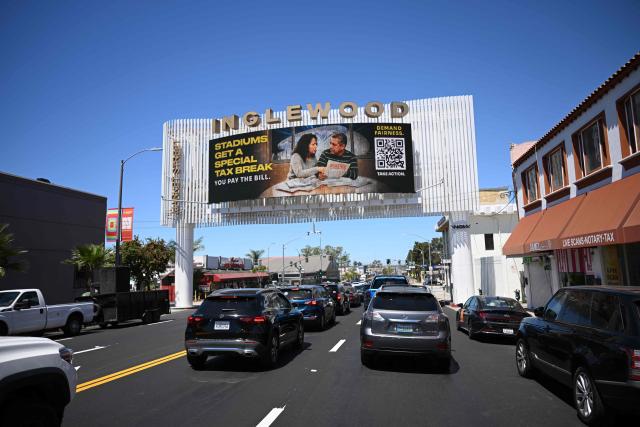 Vehicles drive in traffic below a digital billboard that reads “Stadiums Get A Special Tax Break You Pay The Bill” ahead of the 2026 FIFA World Cup in Inglewood, California, on May 29, 2026. (Photo by Patrick T. Fallon / AFP)