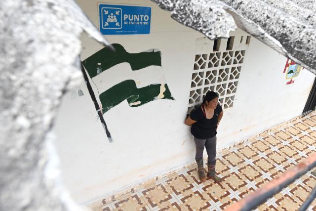 Colombian school teacher Flor Valencia stands at a school as is seen through a hole in a roof caused by an explosion near Suarez, Cauca department, Colombia on May 27, 2026. Surrounded by Andean mountains shrouded in clouds and tropical vegetation, Suarez is a rural village in the Cauca department located near a military base that is constantly under attack by dissident groups that broke away from the 2016 peace agreement with the now-defunct FARC guerrilla group. Locals will elect the successor to President Gustavo Petro on May 31, 2026, the first left-wing leader in the country's history who unsuccessfully attempted to negotiate peace with armed groups. (Photo by Joaquín SARMIENTO / AFP)