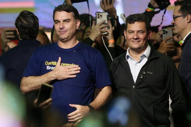 Brazilian senator and presidential hopeful Flavio Bolsonaro (L) and senator Sergio Moro (R) gesture during a rally to launch Moro's candidature for governor of Parana in Curitiba, Parana state, Brazil on May 29, 2026. (Photo by Albari Rosa / AFP)
