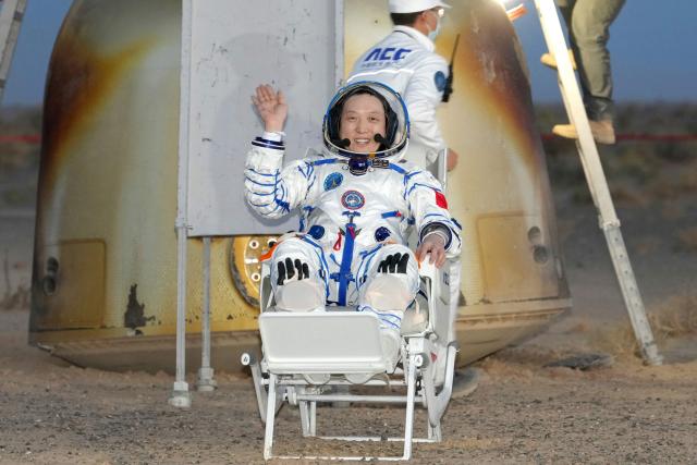 Shenzhou-21 astronaut Zhang Hongzhang waves after being carried from the Shenzhou-22 spacecraft after landing in China’s northern Inner Mongolia region on May 29, 2026. China's Shenzhou-21 crew returned to Earth aboard the Shenzhou-22 spacecraft on May 29 after seven months in space. (Photo by CNS / AFP) / China OUT