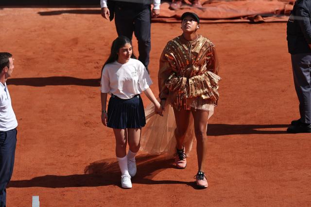 Japan's Naomi Osaka walks on court with a mascot for her women's singles match against US Iva Jovic on day 7 of the French Open tennis tournament on Court Suzanne-Lenglen at the Roland-Garros Complex in Paris on May 30, 2026. (Photo by Anne-Christine POUJOULAT / AFP)