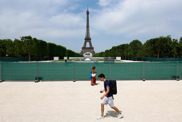 Pedestrians walk past a barriered-off zone were workers prepare to build a stage on the Champs-de-Mars to be used in case of Paris' victory, on May 30, 2026 ahead of the UEFA Champions League Final football match between Paris Saint-Germain (PSG) and Arsenal FC taking place in Budapest. Paris Saint-Germain are aiming to make their mark on football and go down in history by securing a second consecutive European during their Champions League final against Arsenal in Budapest, but the Gunners are hoping to build on their Premier League title to write their own chapter in the sports history. (Photo by Kenzo TRIBOUILLARD / AFP)
