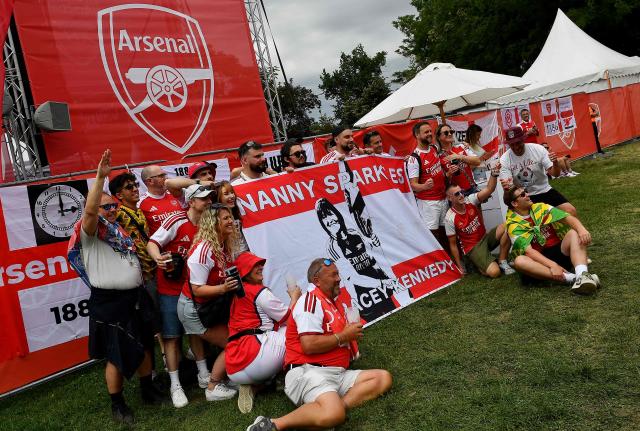 Arsenal fans pose with a banner for late Arsenal fan Anne Tracey Kennedy, also known as Nanny Sparkles, at the City Park in Budapest on May 30, 2026, prior to the UEFA Champions League final football match between Paris Saint-Germain (PSG) and Arsenal FC. (Photo by Ferenc ISZA / AFP)