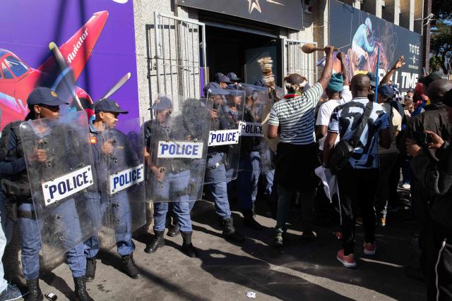 South African Police Service officers block access to a building used by drug dealers to a group of people, many carrying sticks and clubs, during a protest against illegal immigrants organised by March and March in Goodwood, a Cape Town suburb, on May 30, 2026. (Photo by RODGER BOSCH / AFP)
