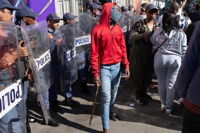 A protester walks past South African Police Service officers during a protest against illegal immigrants organised by March and March in Goodwood, a Cape Town suburb, on May 30, 2026. (Photo by RODGER BOSCH / AFP)