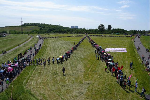 Demonstrators form a large human wind turbine as they take part in a demonstration under the motto "Future instead of gas – Together for the energy transition" organized by environmental organizations BUND, Campact, Fridays For Future, and Greenpeace against the German government's energy policy, on May 30, 2026 in Hamm, western Germany. (Photo by Pau BARRENA / AFP)