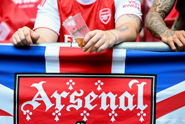 An Arsenal fan holds a glass of beer over an Arsenal logo prior to the UEFA Champions League final football match between Paris Saint-Germain (PSG) and Arsenal FC at the Puskas Arena in Budapest on May 30, 2026. (Photo by NICOLAS TUCAT / AFP)