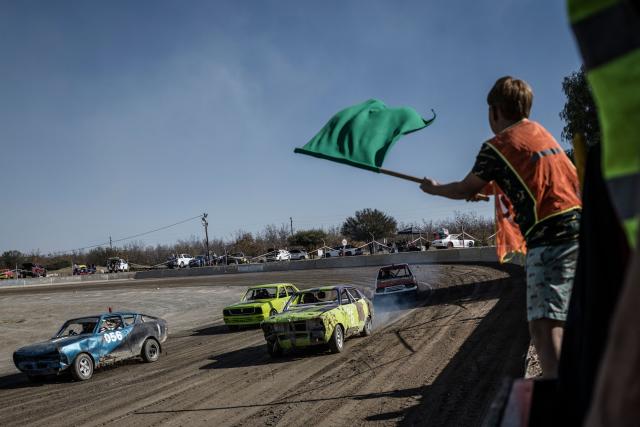 A flag marshall signals to drivers the last warm up lap ahead of an oval dirt racing event at the Orania Ovaalbaan Club in Orania, on May 30, 2026 on the occasion of the Bittereinderdag. Bittereinderdag, celebrated in Orania on may 31st,  commemorates the signing of the Treaty of Vereeniging on May 31, 1902, which ended the Second Boer War, and coincide with the 35th anniversary of the foundation of Orania. Established in 1991 after the abolition of the racial laws, Orania is protected under South Africa's constitution, which ensures the right to self-determination. (Photo by MARCO LONGARI / AFP)