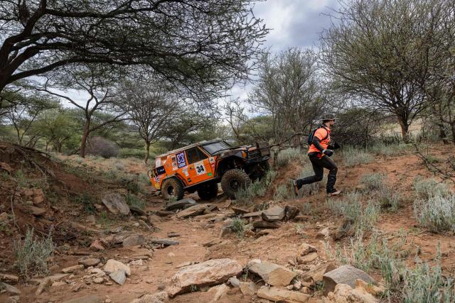 A navigator from team Moto Moto runs ahead of their truck to guide his driver out of a gulley during the Rhino Charge 2026 competition at Ngilai community conservancy in Samburu county on May 30, 2026. The Rhino Charge is an annual bush-bashing competition that attracts extreme off-roading enthusiasts who navigate designated sections of uncharted wilderness in specially self-modified vehicles to raise funds for the conservation of Kenya's water towers.Since its inception in 1989, the Rhino Charge has raised over KES 2.6 billion (approximately $20 million USD) that has been used to construct and maintain some 853 kilometres of protective fences around the country's main water catchments that safeguard indigenous forest and certain threatened species residing therein. (Photo by Tony KARUMBA / AFP)