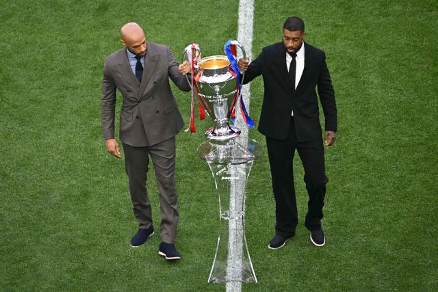 Former Arsenal's French footballer Thierry Henry (L) and former French Paris Saint-Germain's footballer Presnel Kimpembe present the trophy during the opening ceremony of the UEFA Champions League final football match between Paris Saint-Germain (PSG) and Arsenal FC at the Puskas Arena in Budapest on May 30, 2026. (Photo by Attila KISBENEDEK / AFP)
