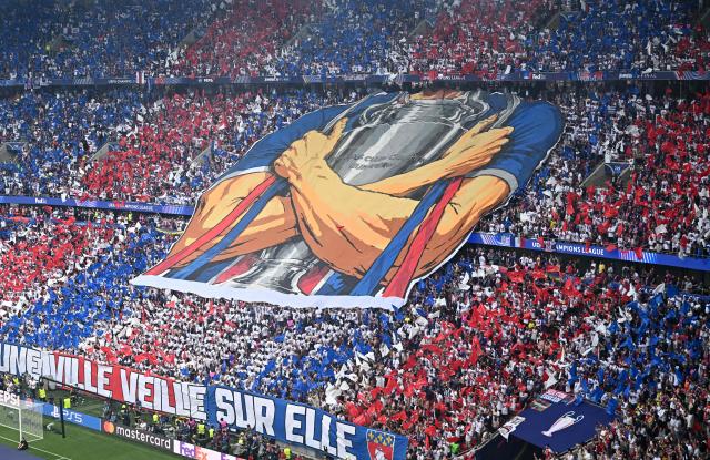 Paris Saint-German (PSG) display a large flag of a player holding the trophy as they  cheer for their team ahead of the UEFA Champions League final football match between Paris Saint-Germain (PSG) and Arsenal FC at the Puskas Arena in Budapest on May 30, 2026. (Photo by Attila KISBENEDEK / AFP)